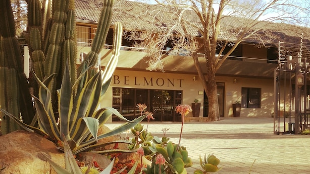 Un edificio con un letrero que dice "BELMONT" y un jardín con diversos cactus y suculentas.