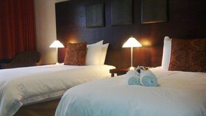Una habitación de hotel con dos camas, cada una con una almohada y una lámpara.