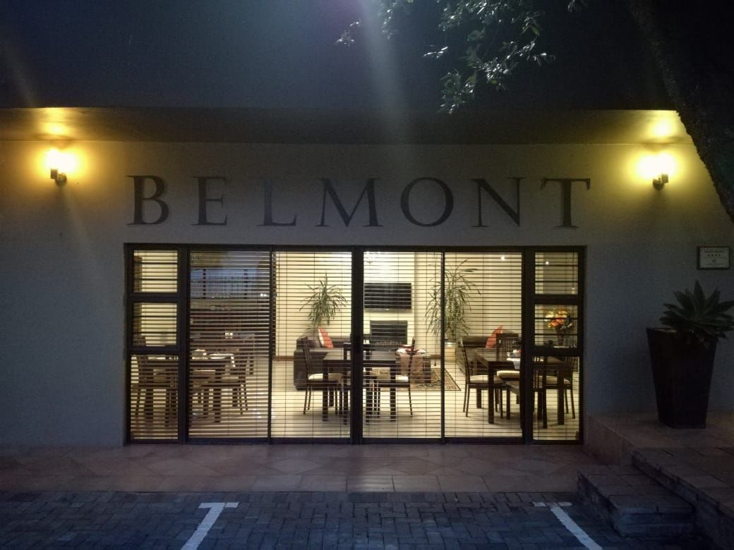 Entrada de un hotel con el nombre 'BELMONT' exhibido sobre las puertas.