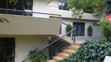 Un immeuble résidentiel à plusieurs étages, doté d’un escalier, de plantes en pot et d’un panneau indiquant la sortie de secours en cas d’incendie.