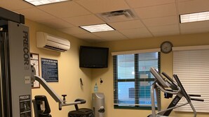 Una palestra con attrezzature per esercizi, un orologio e un condizionatore d'aria a parete.
