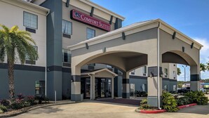 A hotel with a modern facade, a prominent sign reading "Comfort Suites," and an entrance with a covered walkway. - Comfort Suites Sulphur - Lake Charles (Sulphur)