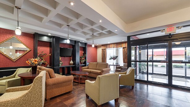A lobby with a sofa, chairs, a mirror, and a flower arrangement. - Comfort Suites Sulphur - Lake Charles (Sulphur)