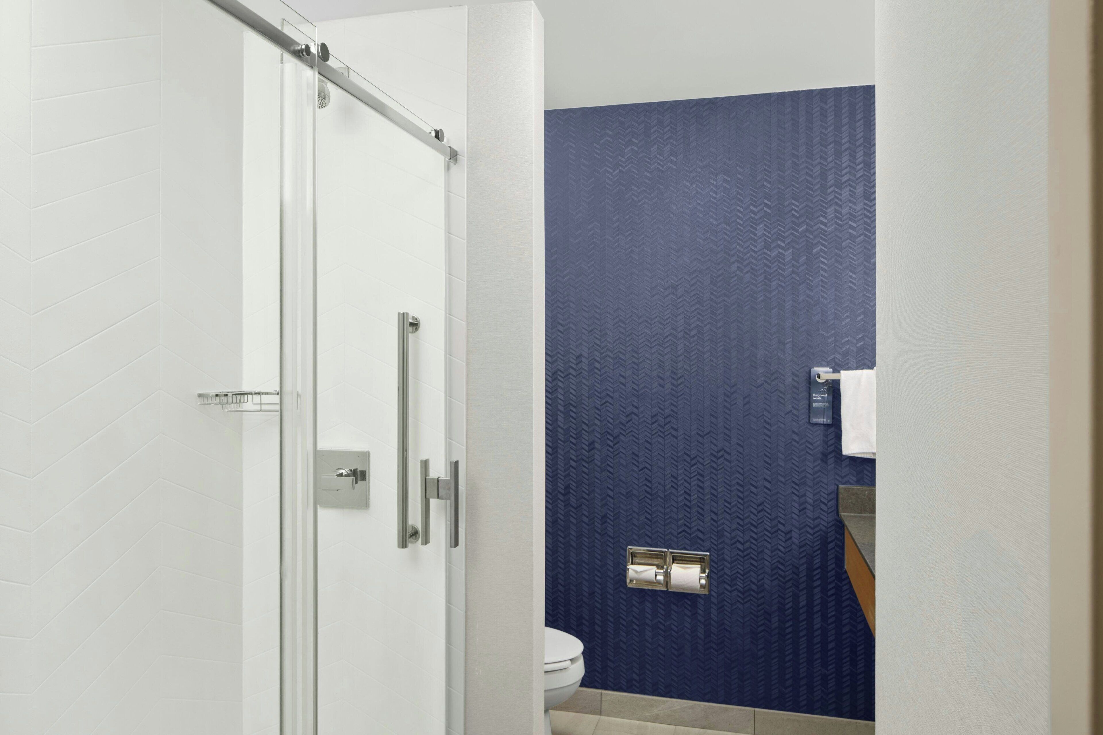 Un baño con ducha, inodoro y dispensador de toallas.
