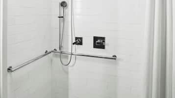 A white tiled shower area with a handheld showerhead, a handheld shower attachment, and a control panel.