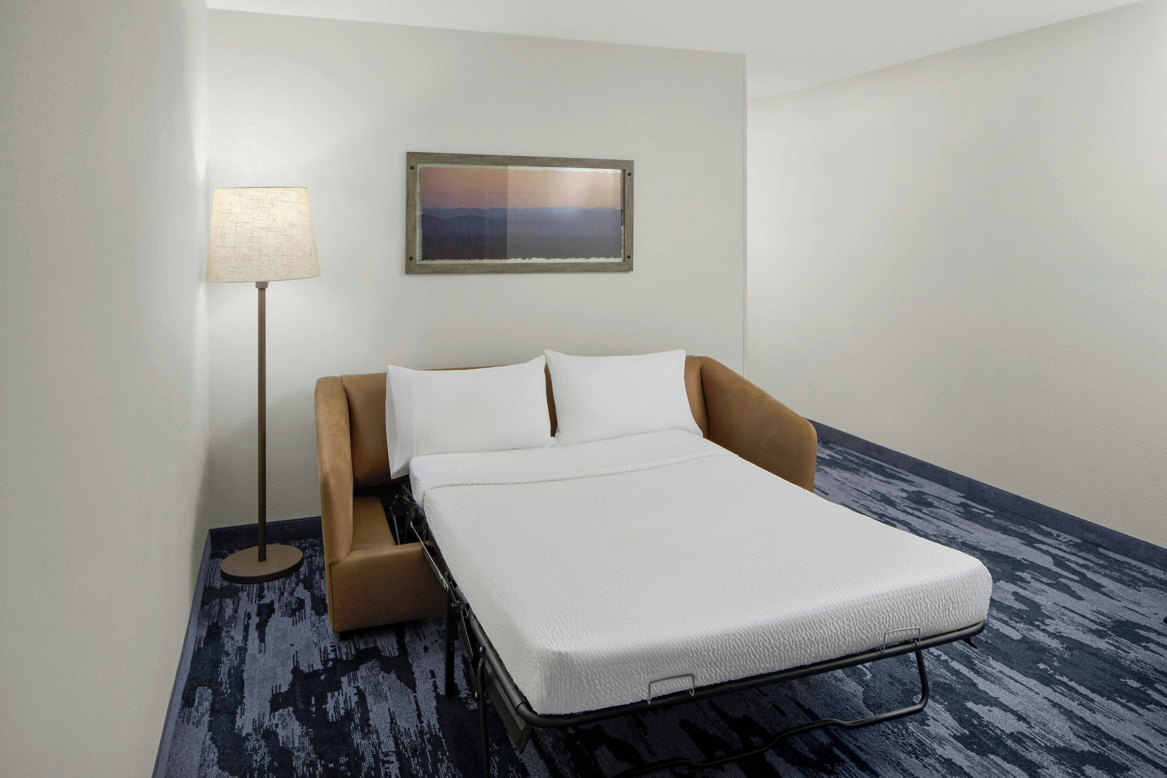 Un lit simple avec un matelas blanc dans une chambre d’hôtel.