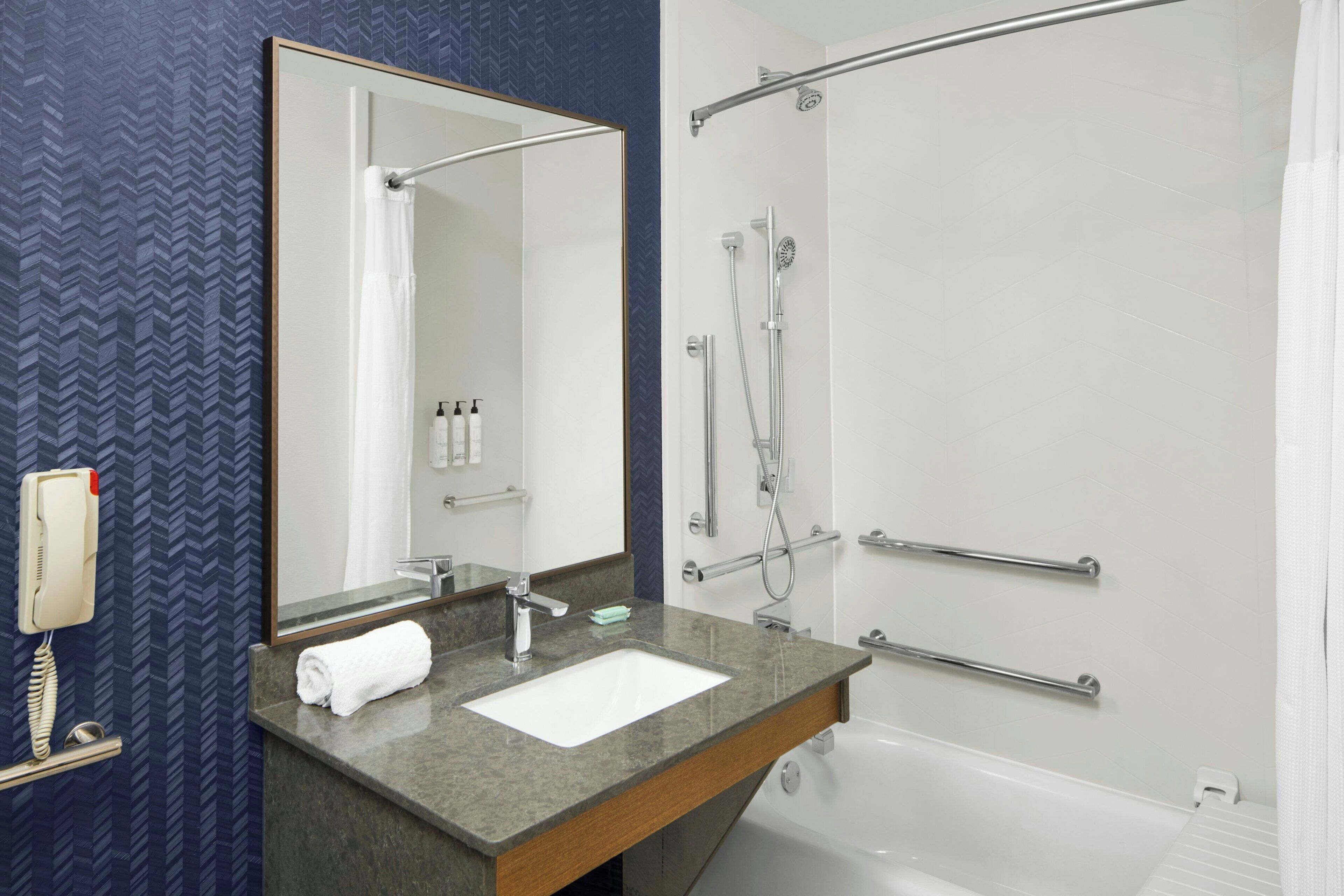 Une salle de bain équipée d’un lavabo, d’un miroir, d’une douche et d’un porte-serviettes.