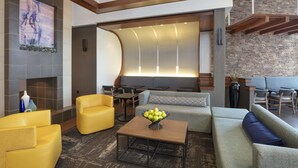 A modern lobby with a fireplace, seating area, and a stone wall. - Hyatt Place Reno Tahoe Airport (Reno)