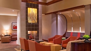 A modern lobby with leather sofas, a wooden reception desk, and a large abstract art piece on the wall. - Hyatt Place Reno Tahoe Airport (Reno)