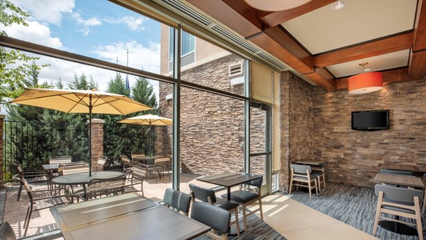 An outdoor dining area with stone walls, large windows, and outdoor seating. - Hyatt Place Reno Tahoe Airport (Reno)