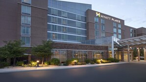 A modern hotel building with a glass facade, a covered entrance, and a well-lit exterior. - Hyatt Place Reno Tahoe Airport (Reno)