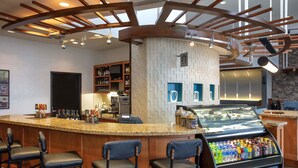 A bar area with a granite countertop, bar stools, a beverage dispenser, and a wall-mounted TV. - Hyatt Place Reno Tahoe Airport (Reno)
