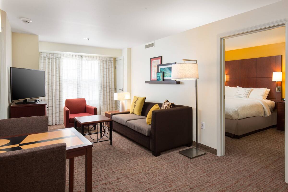 A hotel room with a bed, a sofa, a TV, and a desk.