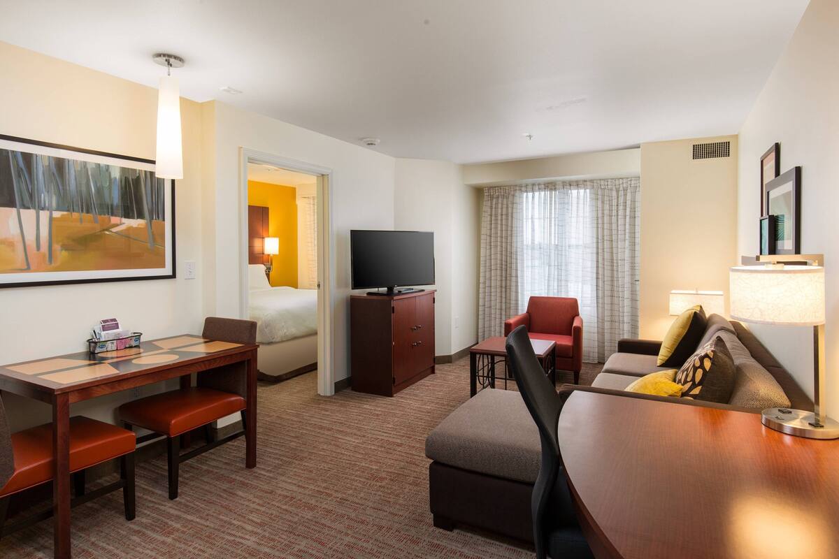 A hotel room with a bed, a desk, a television, a chair, and a sofa.