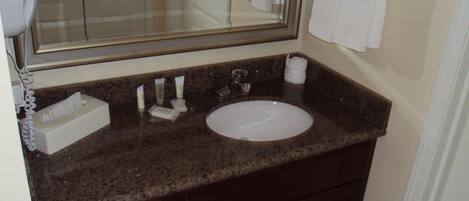 A bathroom with a sink, mirror, towel rack, and toiletries.