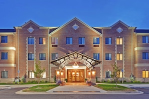 A multi-story hotel with a central entrance featuring a covered walkway and a large door. - Staybridge Suites Indianapolis-Carmel by IHG (Indianapolis)