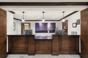 A reception desk with two computers, a large framed picture of a bridge, and a sign indicating the manager's name. - Staybridge Suites Indianapolis-Carmel by IHG (Indianapolis)