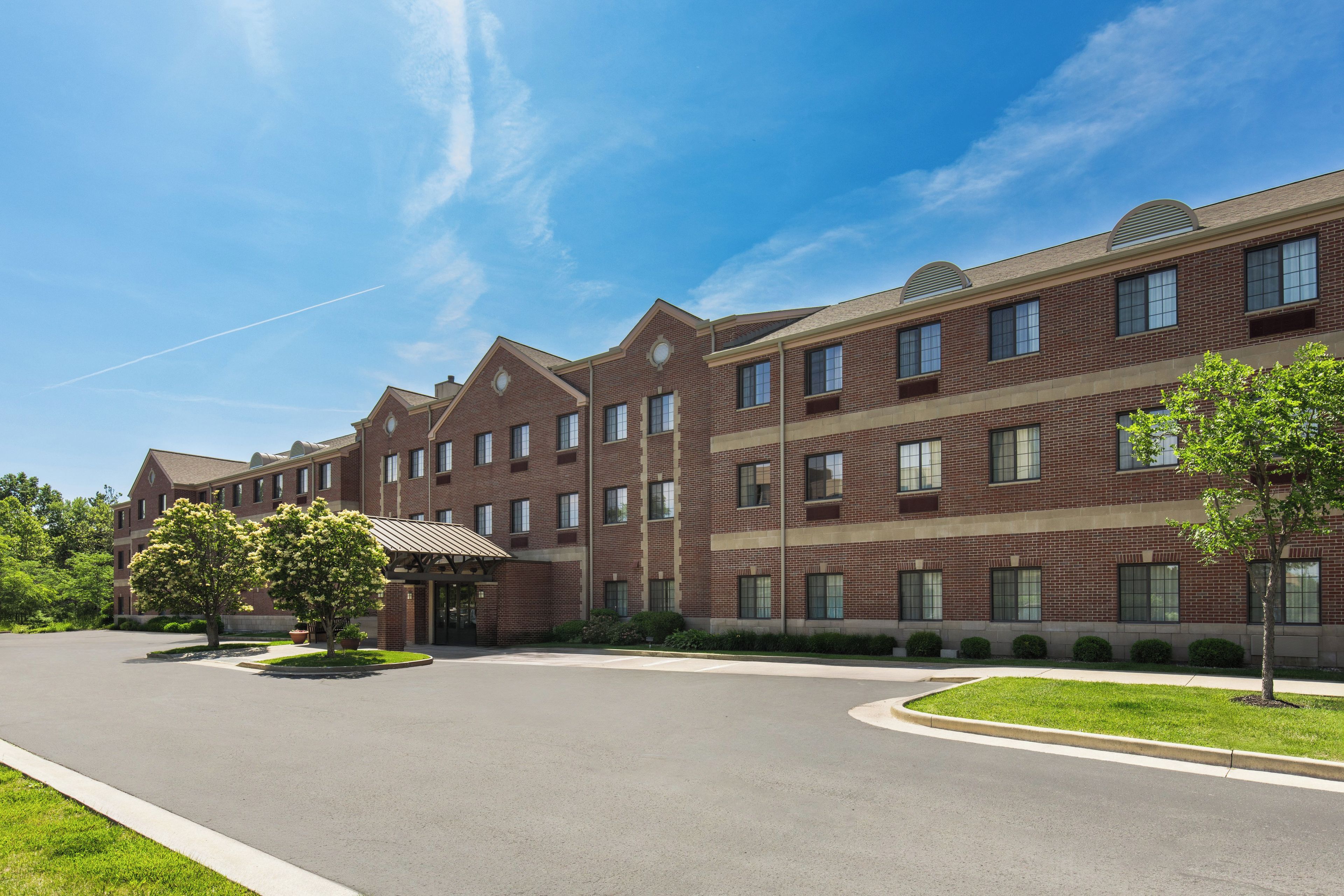 A multi-story brick building with a covered entrance and a parking lot.