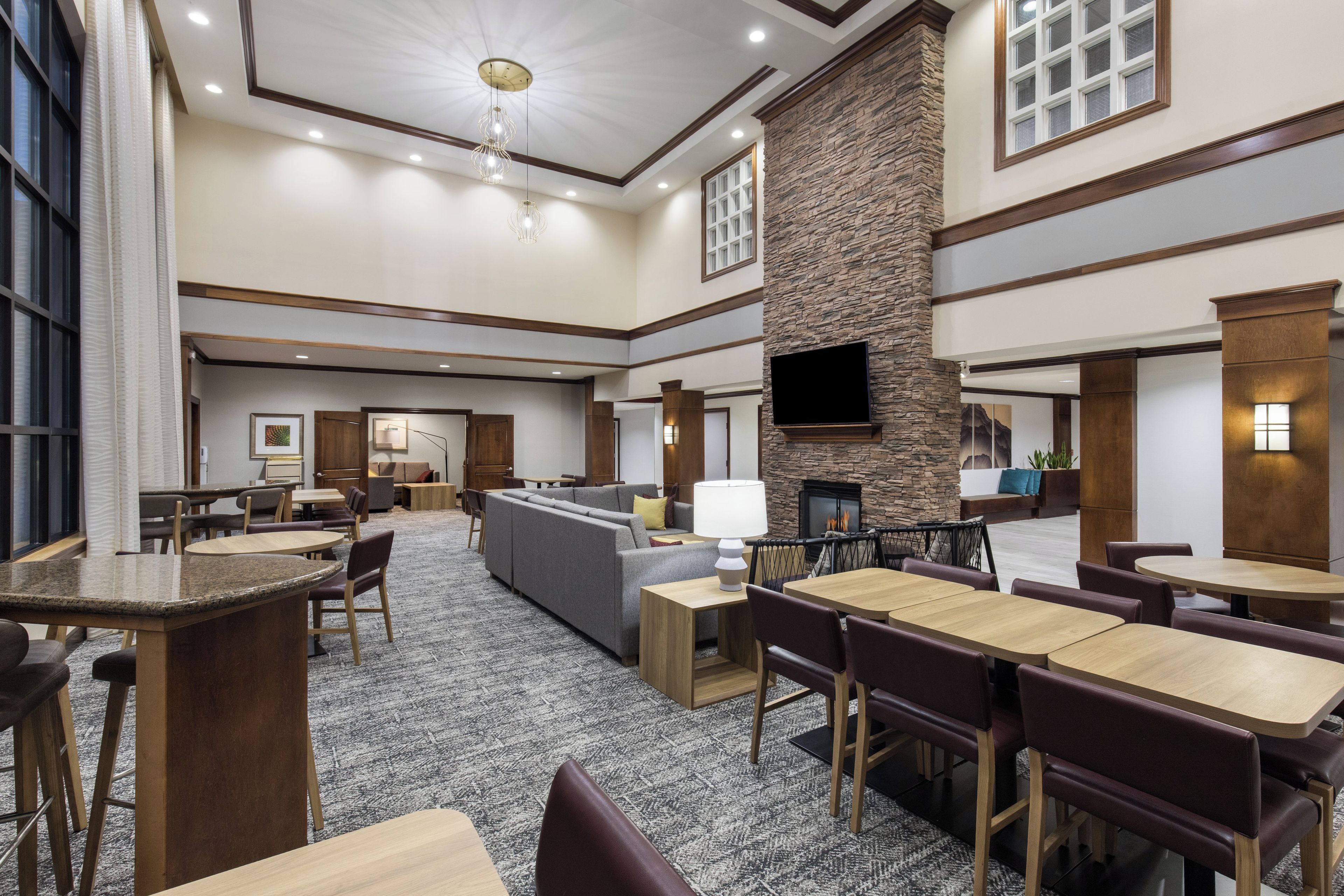 A hotel lobby with a fireplace, seating areas, and a television.