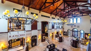Um hall amplo com tetos altos, lustres e uma escadaria central.