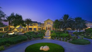 A large, well-lit hotel with a central courtyard, multiple guest rooms, and a landscaped garden. - Arabian Ranches Golf Club (Dubai)