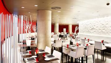 Een modern restaurant met witte stoelen en tafels, rode accenten en een opvallend plafondontwerp.