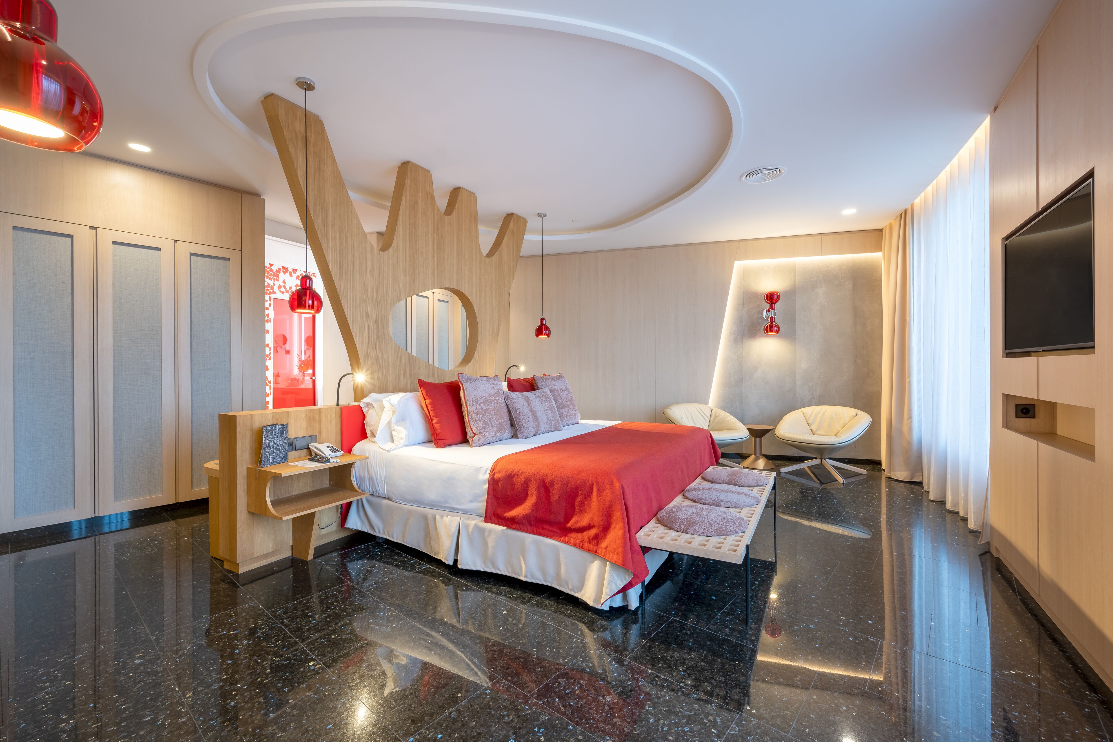A modern hotel room with a large bed, a desk, and a chair.
