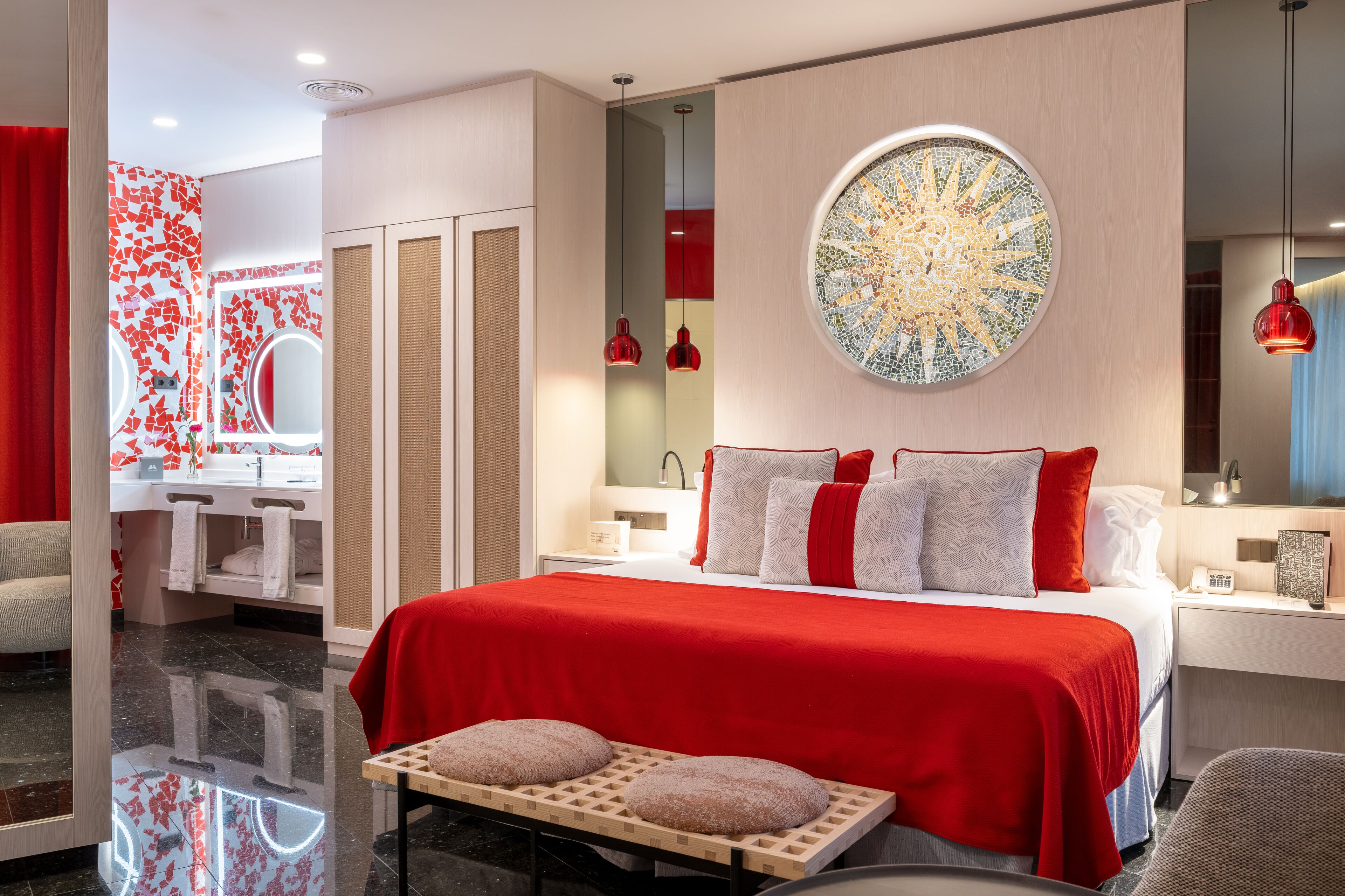 Una habitación de hotel moderna con una cama grande, un tocador con espejo y una pared de acento roja.