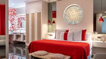 Una habitación de hotel moderna con una cama grande, un tocador con espejo y una pared de acento roja.