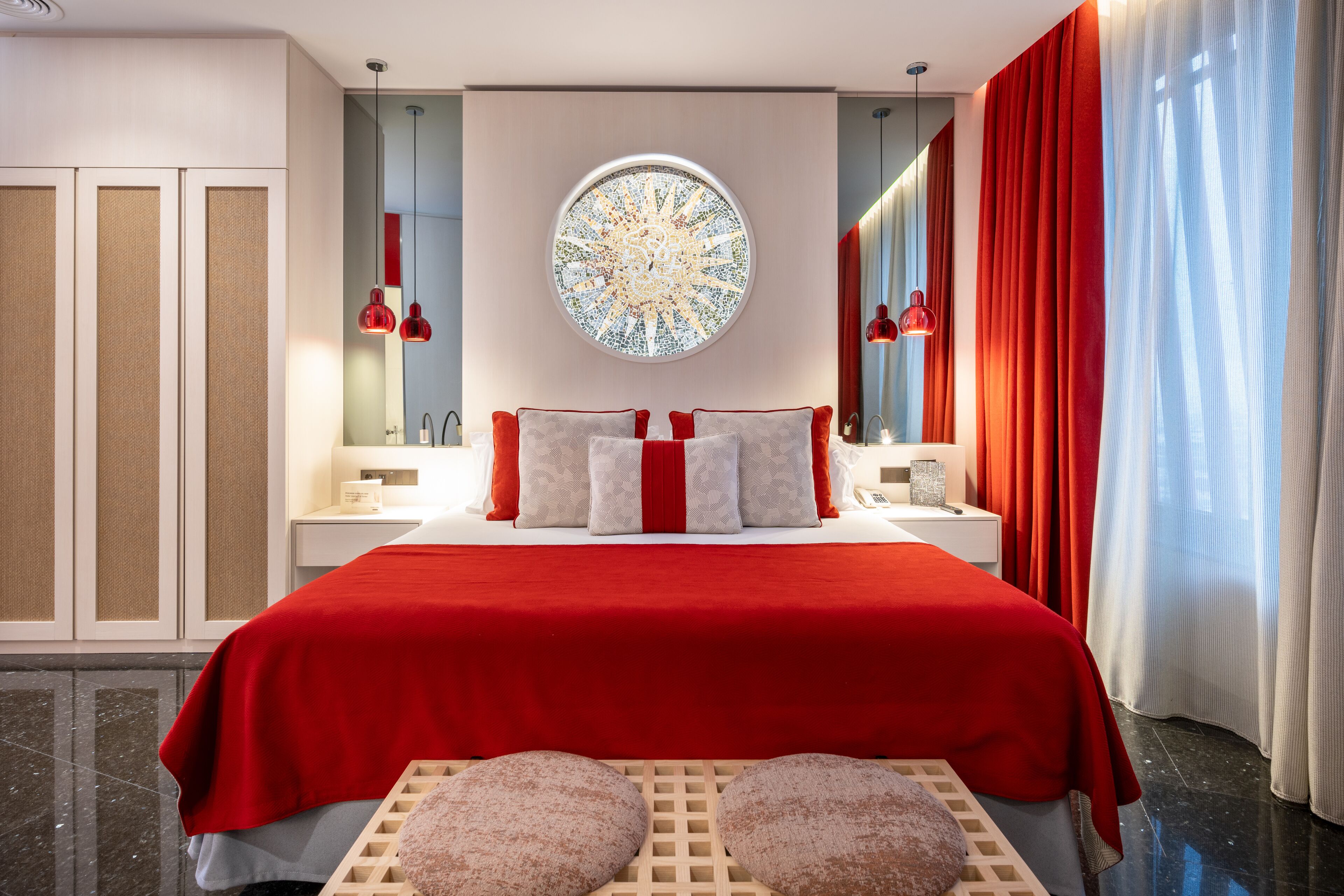 Um quarto moderno com uma cama grande, um espelho redondo e uma cortina vermelha.