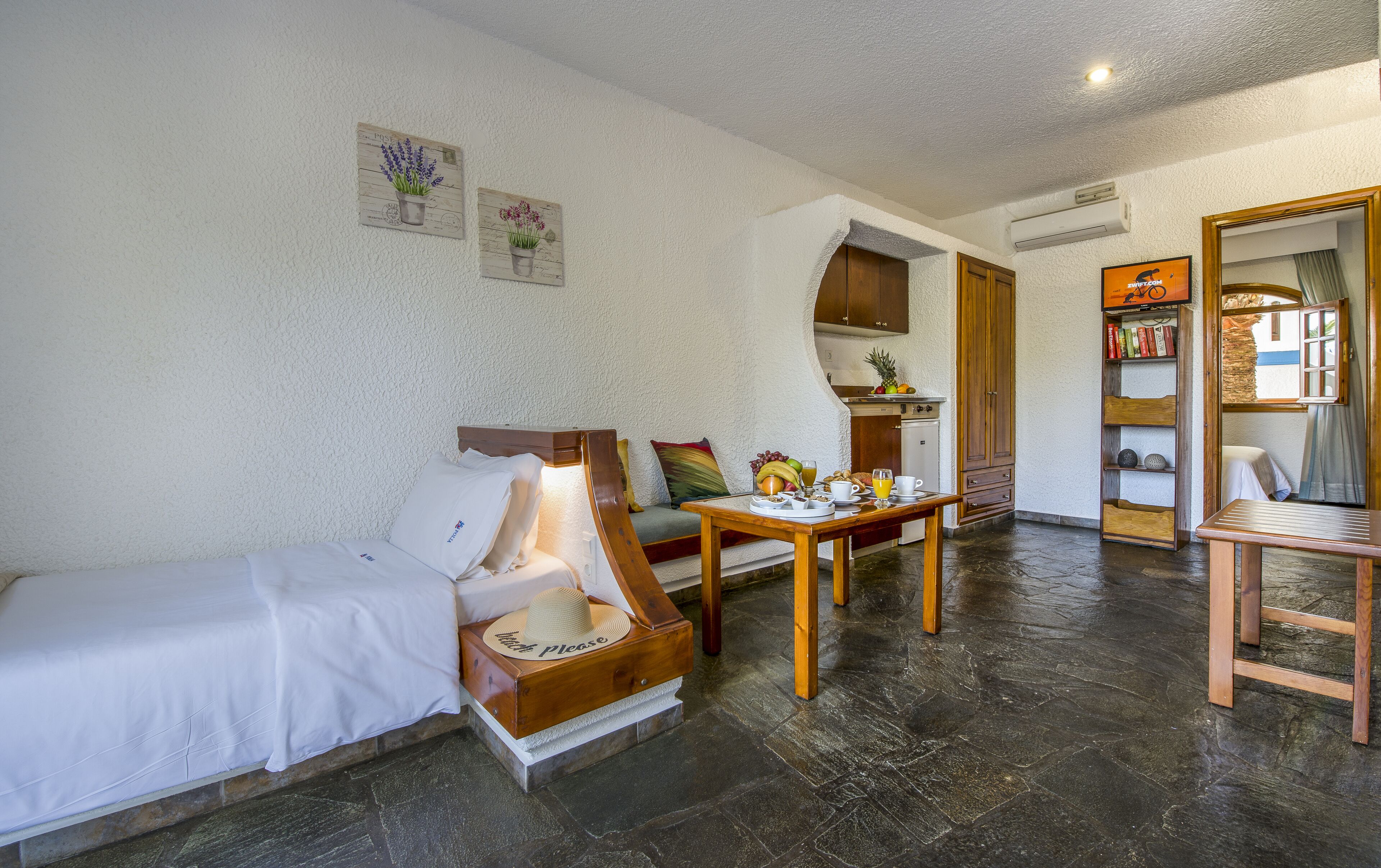 A cozy room with a bed, a wooden table with breakfast, a sofa, and a bookshelf.