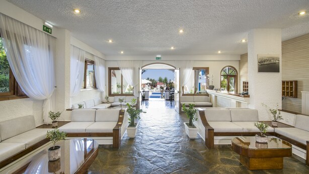A spacious lobby with a central pathway, white sofas, potted plants, and a view of the outdoors. - Folia Apartments (Chania)
