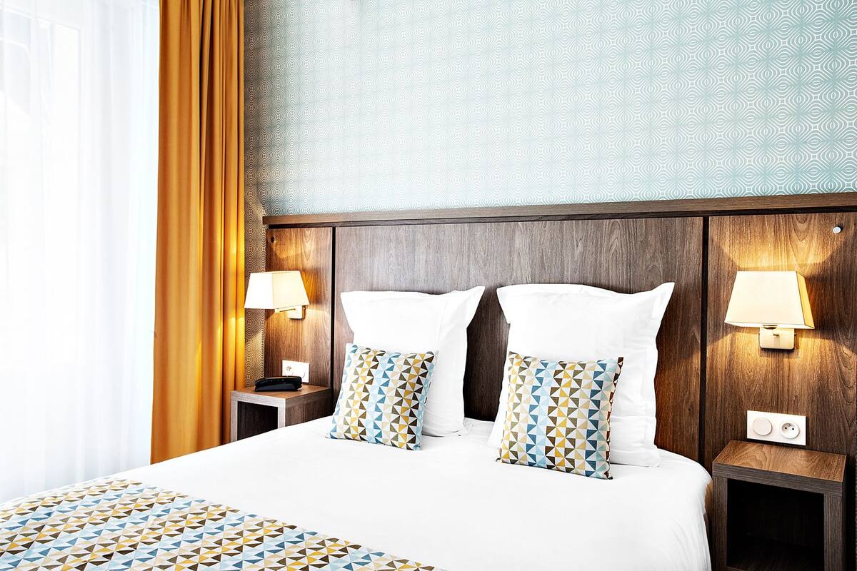 Une chambre d’hôtel avec un grand lit, deux lampes de chevet et une couvre-lit à motifs.