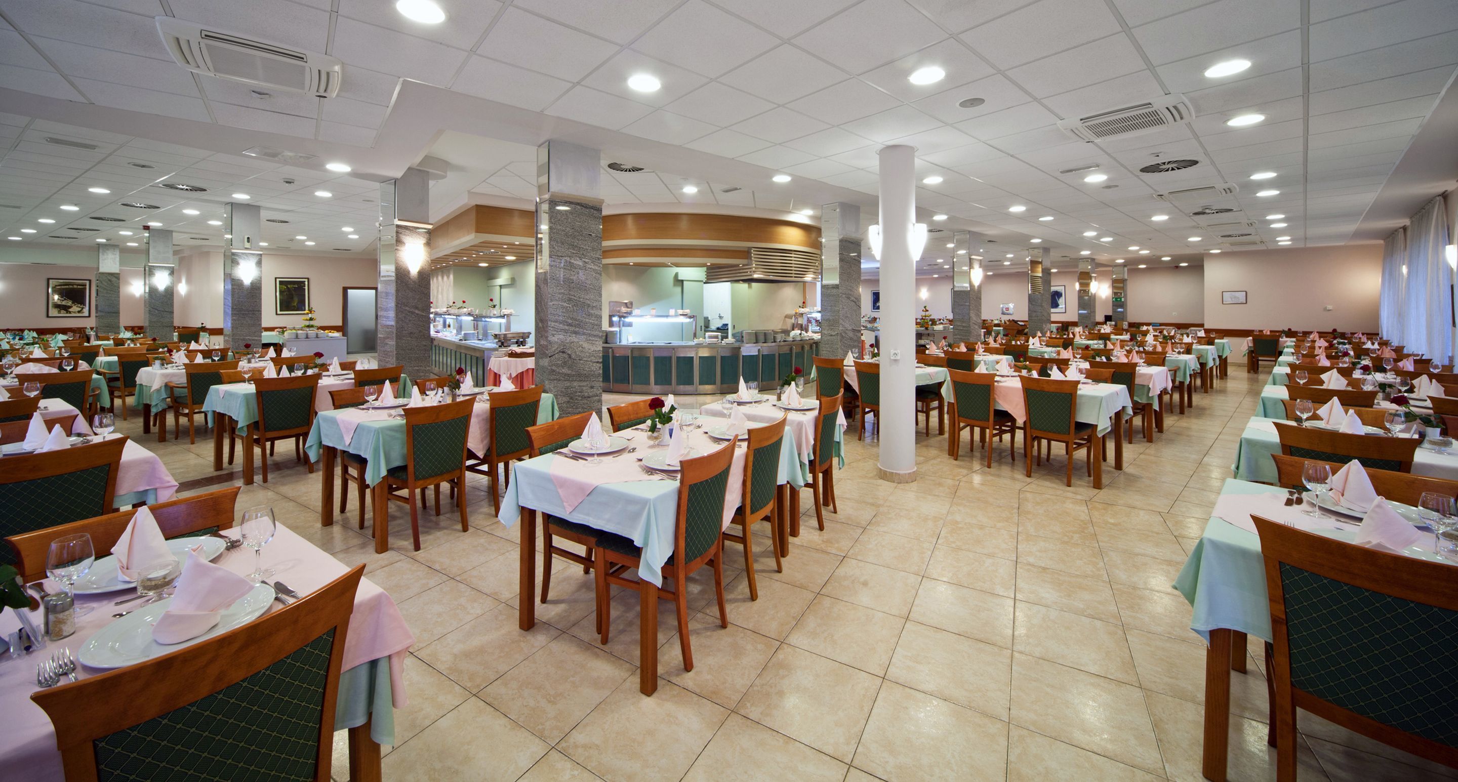 A spacious dining area with multiple tables and chairs, a central counter, and a tiled floor.