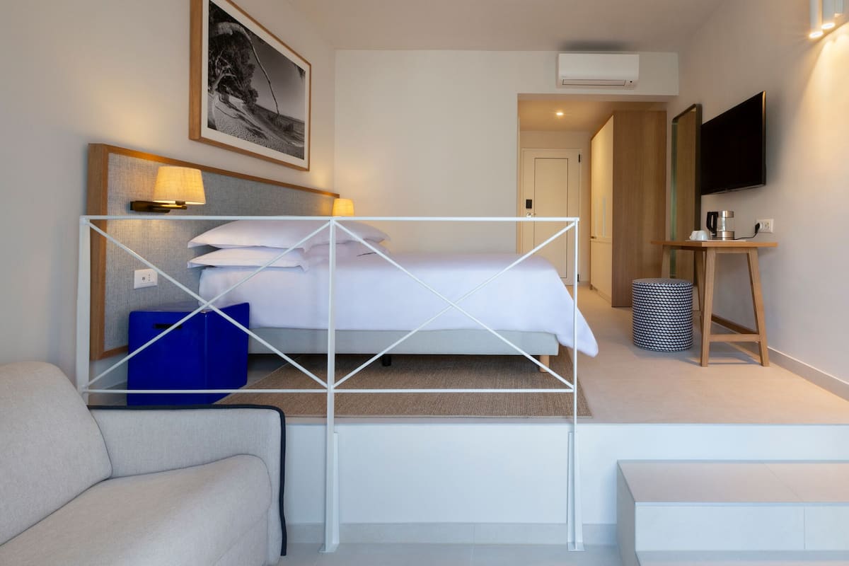 Una habitación de hotel con una cama, un sofá, un televisor y una cafetera.