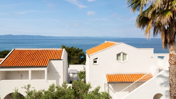 A coastal residential area with white buildings and orange-tiled roofs, overlooking the sea. - Bluesun Holiday Village Afrodita (Tucepi)