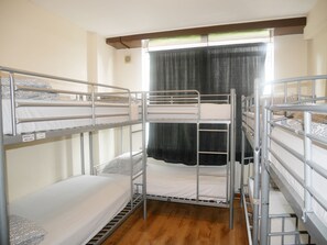 A bunk bed room with metal railings, a window with curtains, and a wooden floor. - Kensal Green Backpackers 1 (London)
