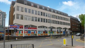 A multi-story building with a storefront featuring international flags and food advertisements. - Kensal Green Backpackers 1 (London)