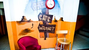 A wall with a clock, a cafe sign, and a chair. - Kensal Green Backpackers 1 (London)