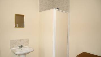 A bathroom with a white sink, a mirror, and a shower enclosure.