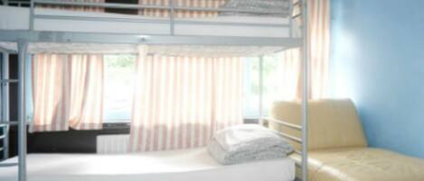 A bunk bed with a mattress and pillows, a window with curtains, and a chair.