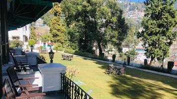 Una terraza con mobiliario y vistas a un césped verde y árboles.