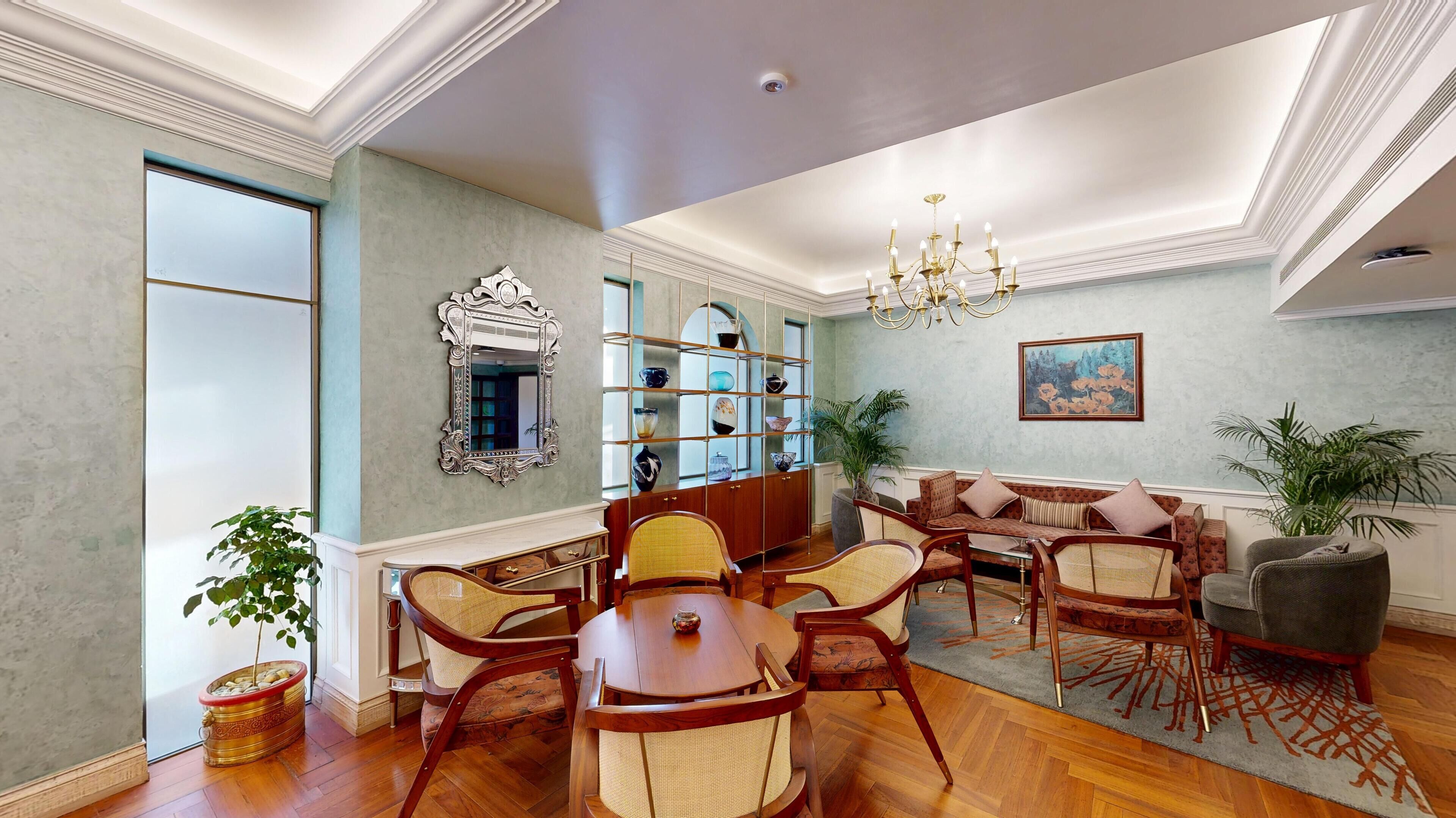 A spacious living room with a wooden coffee table, wicker chairs, a sofa, and a bookshelf.