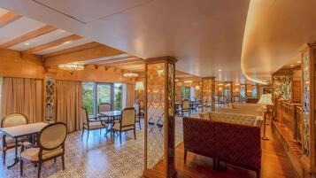 A spacious room with a large dining table, multiple chairs, a sofa, and a patterned rug.