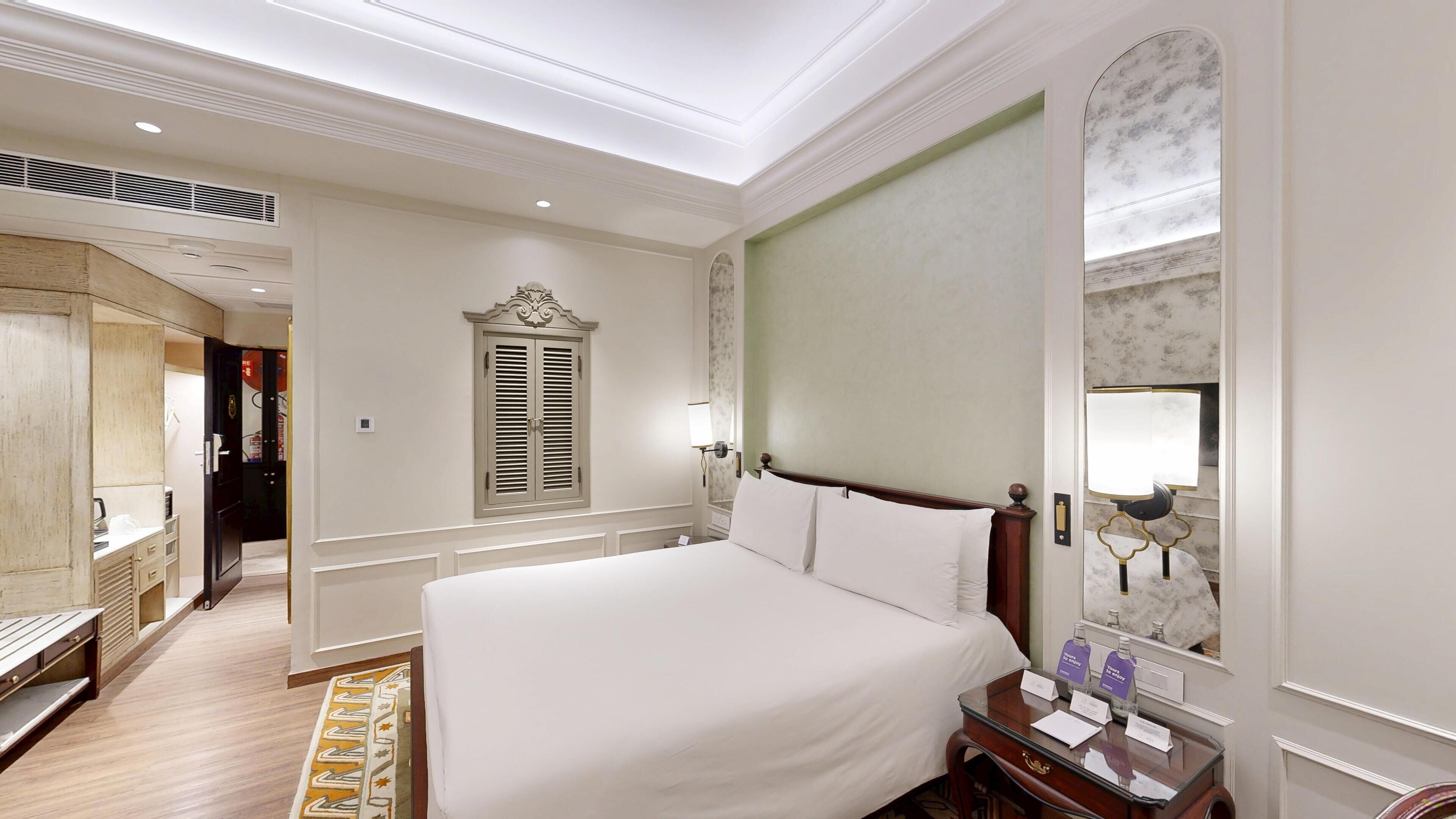 Una habitación de hotel con una cama grande, un tocador con espejo, un escritorio y un armario.