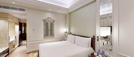 Una habitación de hotel con una cama grande, un tocador con espejo, un escritorio y un armario.