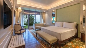 Habitación de hotel con una cama grande, un banco, un sofá, un televisor y vistas al exterior.