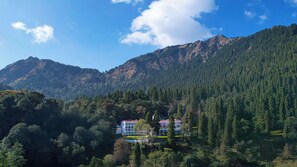 Un hotel ubicado en un valle boscoso, con montañas al fondo.
