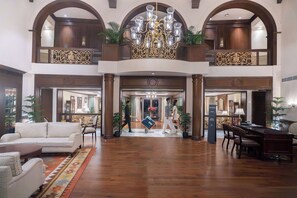 Experience the grandeur of our lobby, featuring a high ceiling, elegant seating area, and beautiful potted plants.