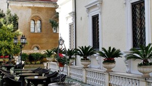 An outdoor patio with tables and chairs, potted plants, and a decorative fountain. - Villa Pinciana (Rome)